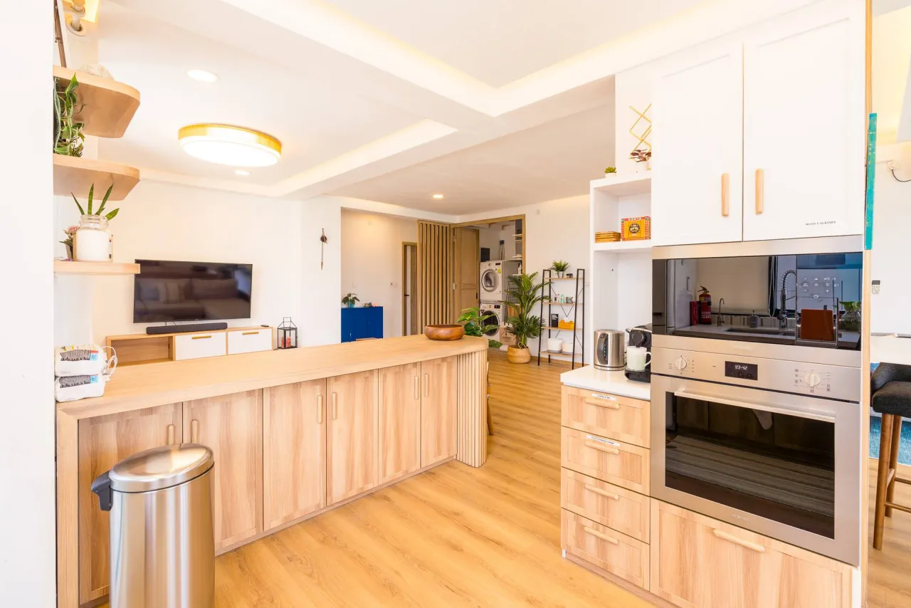 Kitchen island with timber cabinets and a built-in oven, opening onto the living room