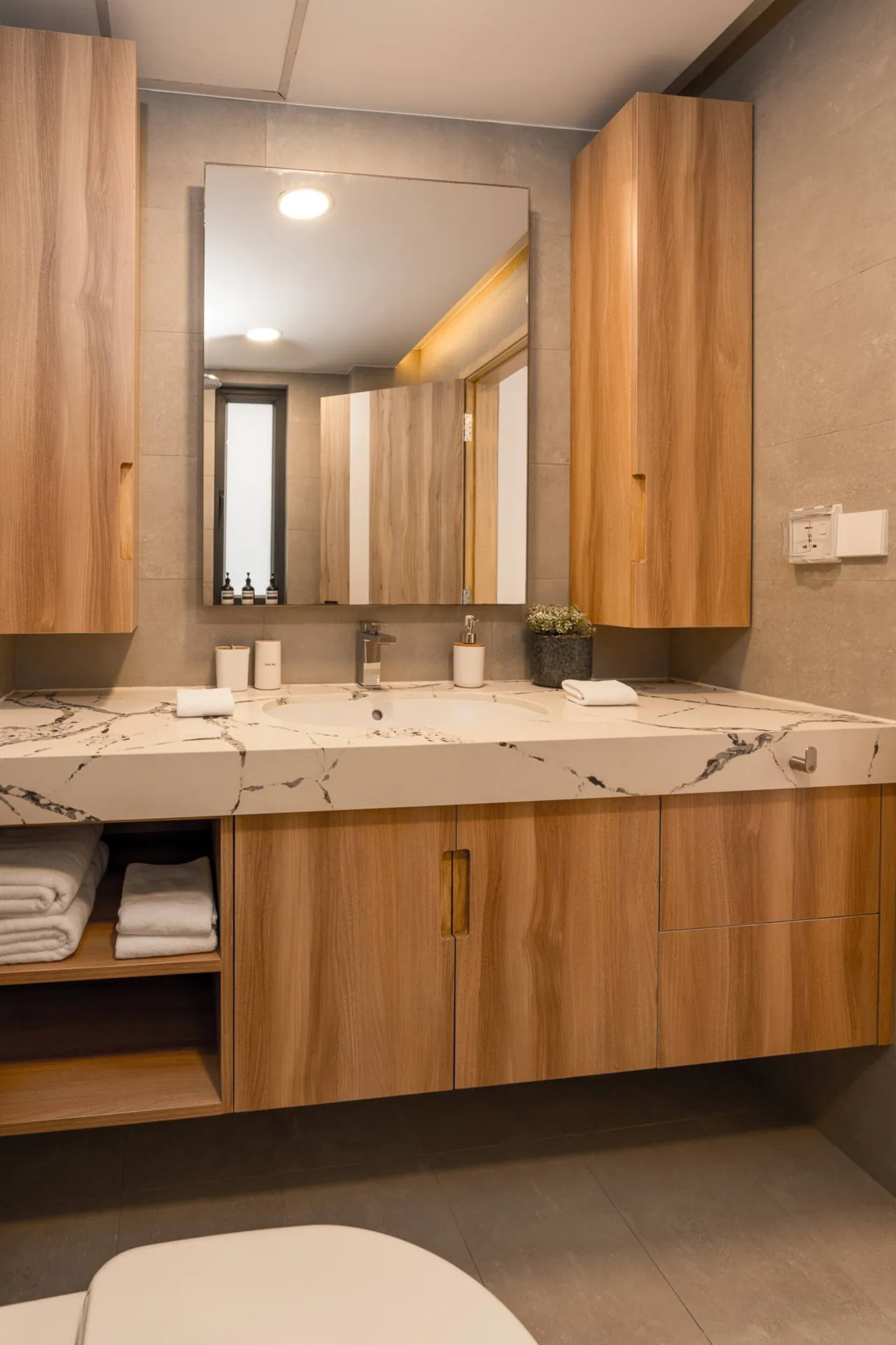 Bathroom with a marble-topped timber vanity, a large mirror and folded towels