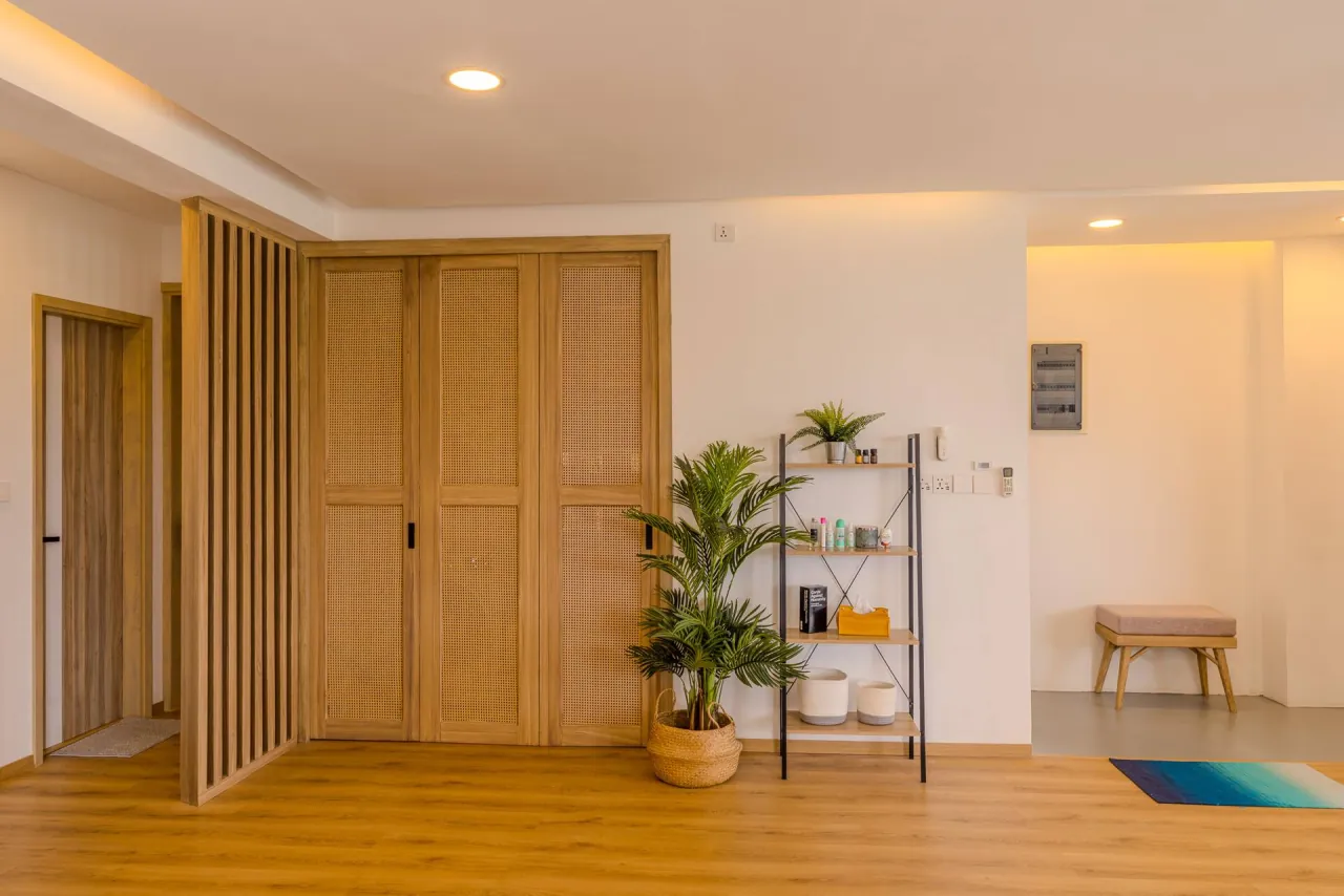 Entrance hall with slatted timber doors, a shelf with plants and a small bench